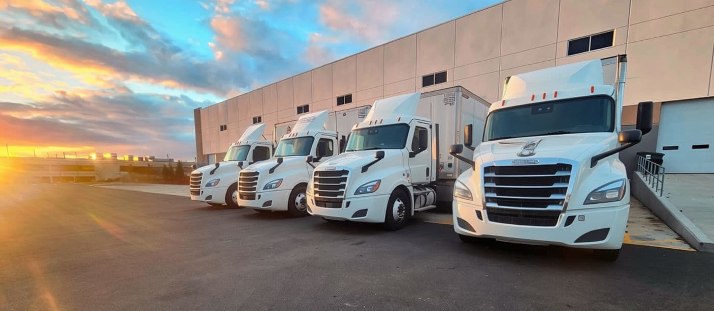 Freight trucks staged at the warehouse loading dock at sunrise