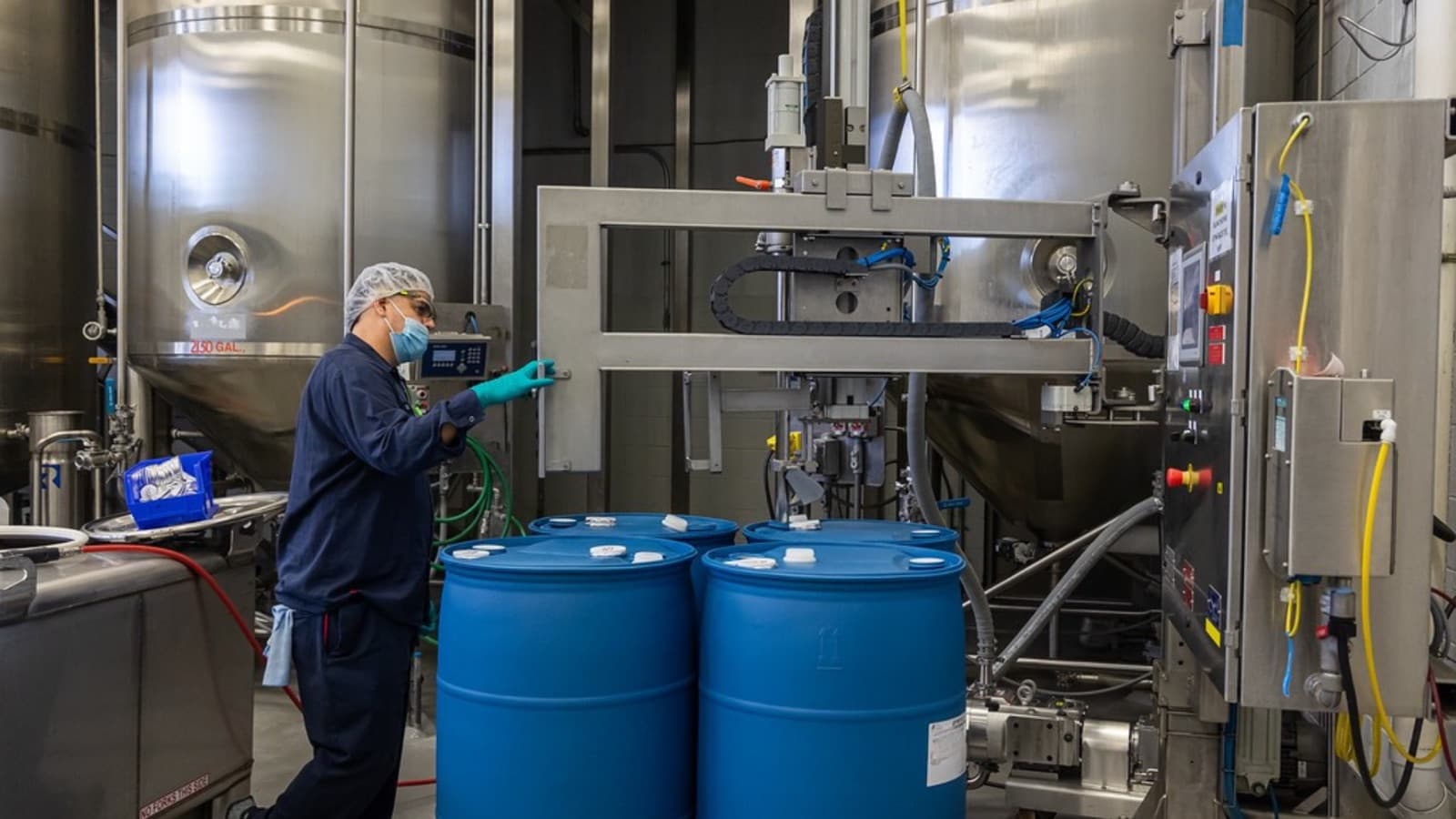An Allen Flavors team member working alongside blending tanks on the warehouse floor